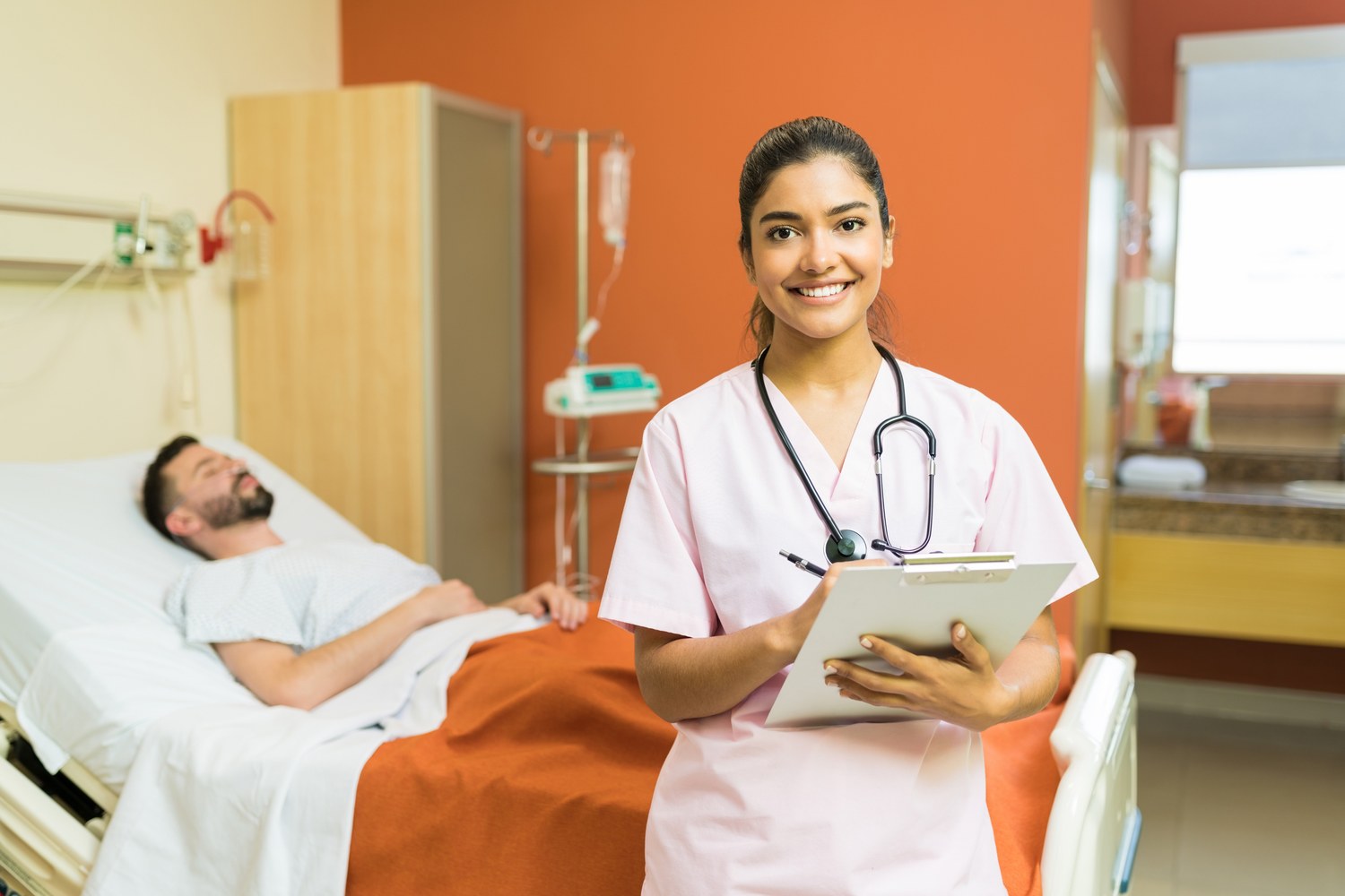 Nurse holding a clipboard beside a patient in a hospital room