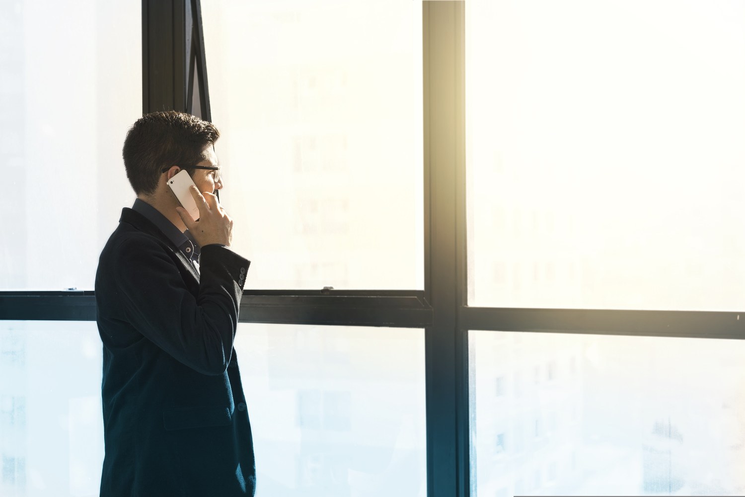 Business professional standing by a large office window