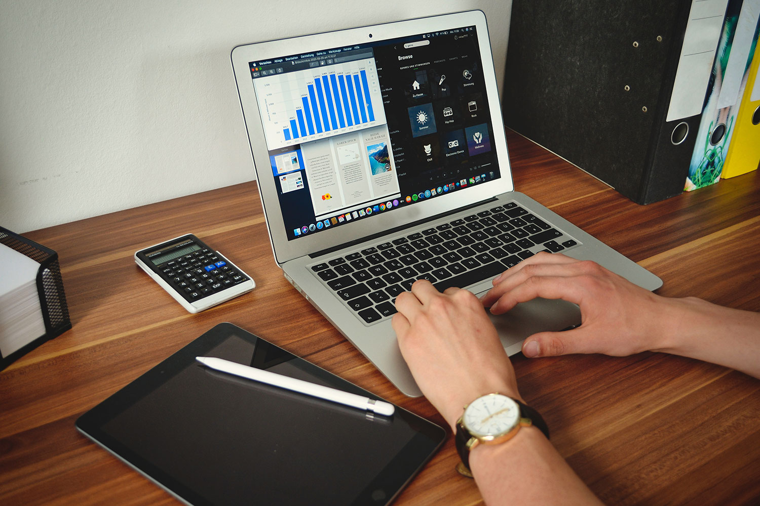 Laptop displaying charts and reports beside a calculator and tablet